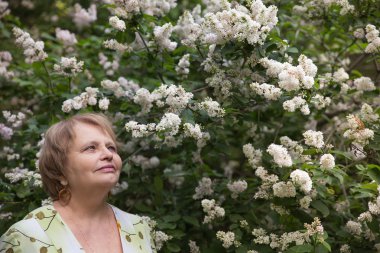 Emekli kadın çiçek bahçesinde
