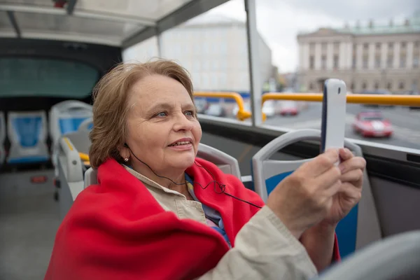 Pensionär kvinna ta bilder via telefon i turistbuss Stockbild