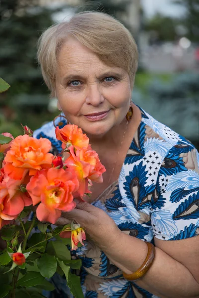 Συνταξιούχος γυναίκα με τριαντάφυλλα στον κήπο — Φωτογραφία Αρχείου
