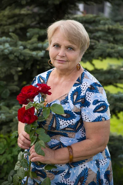 Pensionär kvinna med rosor i trädgården Royaltyfria Stockfoton
