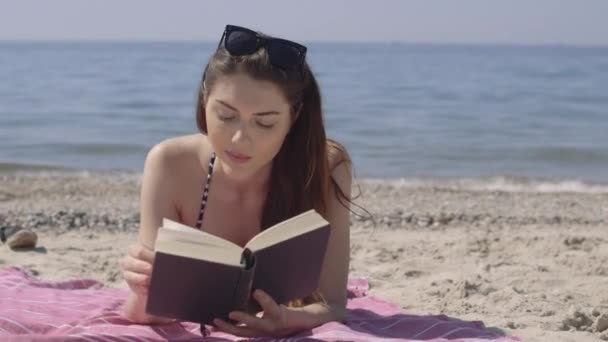 Woman reading book on beach — Stock Video
