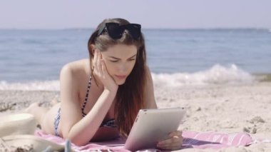 Kadın plajda dijital kitap okuma