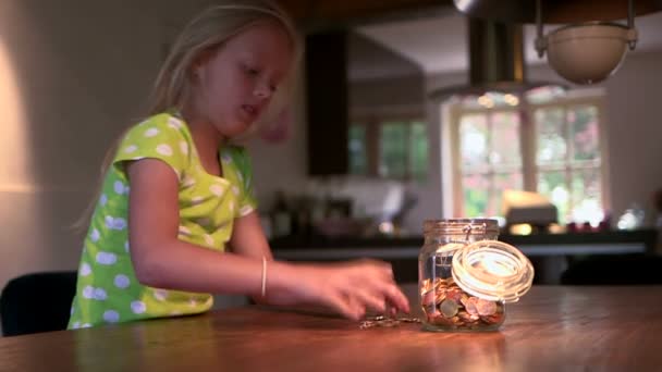 Girl filling coins jar — Stock Video