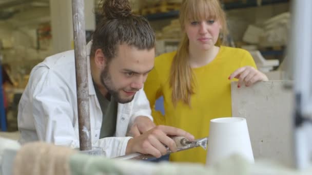 Alfarero masculino enseñando cerámica a la mujer — Vídeo de stock