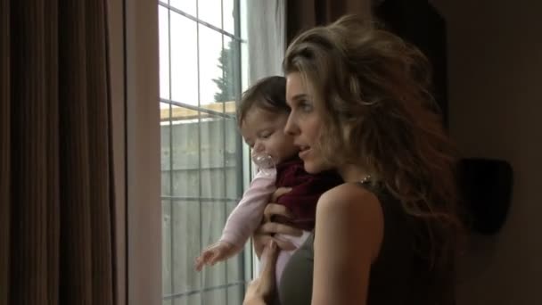 Moeder en baby kijken uit venster — Stockvideo