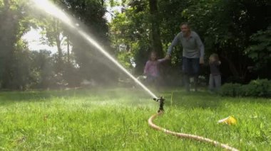 Baba ve kızı bir yağmurlama ile çalışan