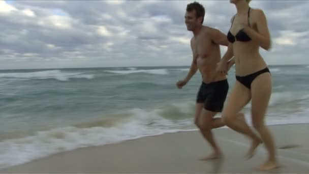 Pareja corriendo en una playa — Vídeo de stock