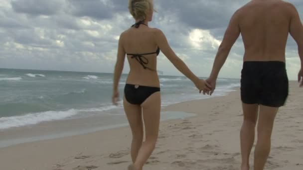 Casal caminhando ao longo de uma praia — Vídeo de Stock