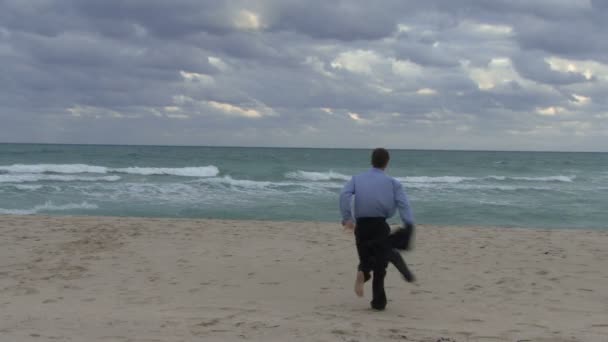Мужчина бежит в океан — стоковое видео