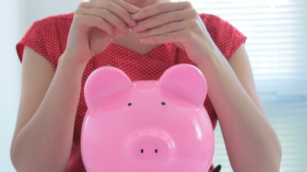 Female putting coins in piggy bank — Stock Video