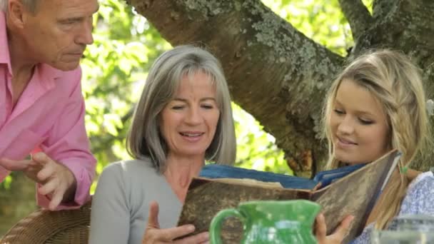 Föräldrar och dotter söker fotoalbum — Stockvideo