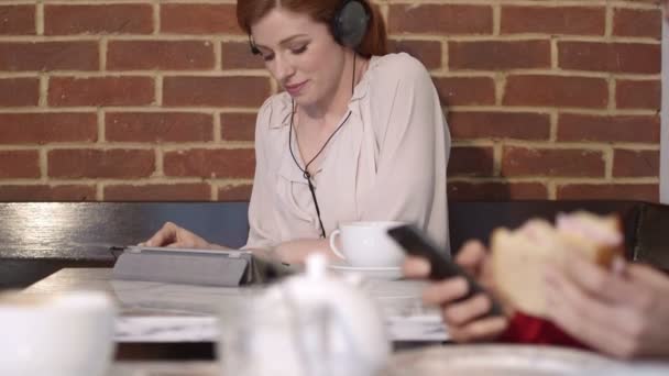 Vrouw luisteren muziek in café — Stockvideo