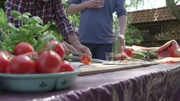 Hombre cortando tomate y hablando — Vídeo de stock