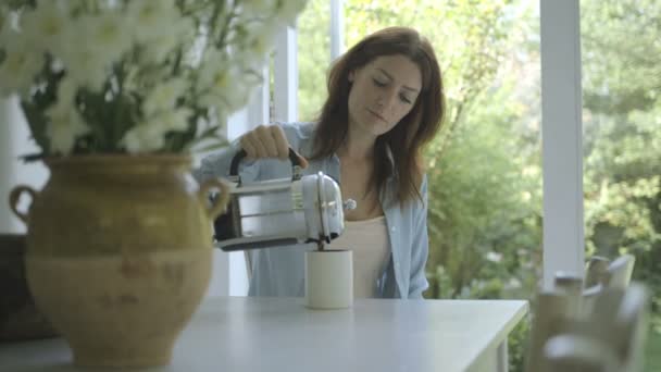 Женщина наливает кофе в чашку и пьет — стоковое видео