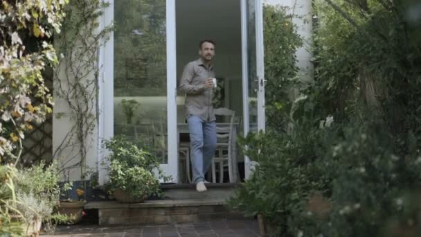 Чоловік п'є каву в саду — стокове відео