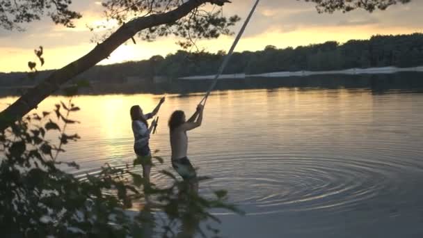 Pareja disfrutando de cuerda swing sobre río — Vídeo de stock