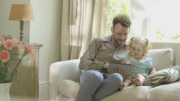 Father showing digital tablet to his daughter — Stock Video