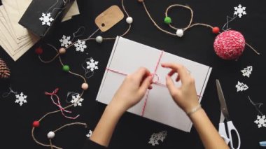 Noel için hazırlanıyorum. Kadınların elleri hediye paketler. Hediye paketi. Kız bir hediye hazırlıyor. Yeni yılın dekoratif unsurları. Şenlik havası. Neşeli arkaplan