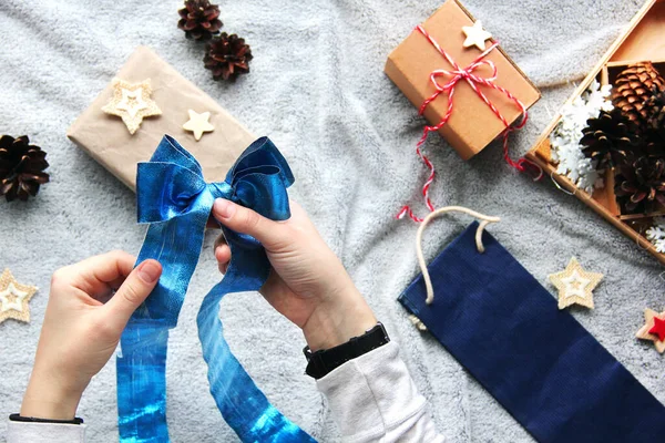 Gift wrapping process. Blue bow. Gifts in craft paper. Festive atmosphere. New Year\'s decor. Minimalistic gift wrapping