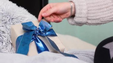 Kız bir hediyeye fiyonk bağlıyor. Hediye paketi. Mavi fiyonklu bir hediye. El işi kağıdında hediye. Güzel mavi fiyonk. Noel zamanı. Yeni Yıl