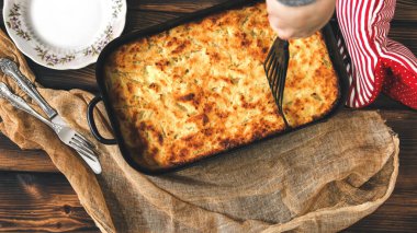 Fırın tepsisinde süzme peynir güveci. Ev yapımı turta. Mutfak eldivenleri. Tatlı.