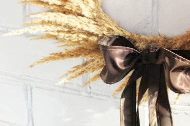 Beyaz tuğla bir duvarın arka planında kurumuş çiçeklerden oluşan bir çelenk. Eski model. İç çelenk. Ev dekorunun bir unsuru olarak kurumuş çiçekler