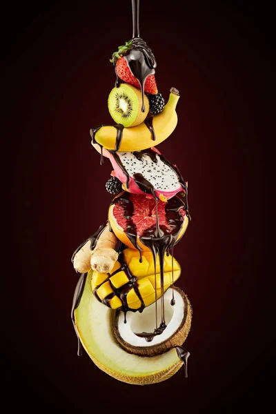 Koyu kahverengi üzerine çikolata dökülmüş meyve yığını