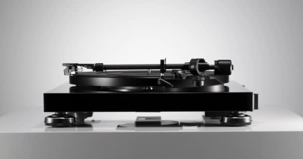 Black varnished record player spinning on white table — Stock Video