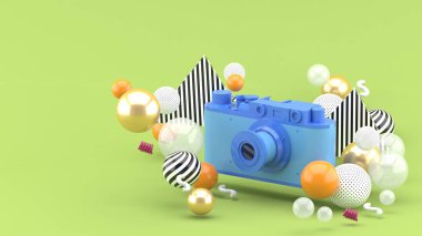 Mavi kamera yeşil arka planda renkli toplarla çevrili. - 3D görüntüleme