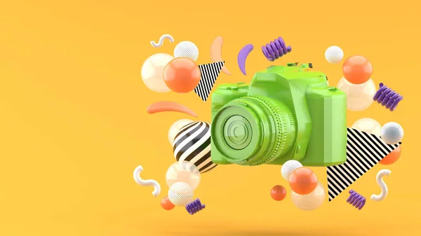 Green camera surrounded by colorful balls on an orange background.-3d render.