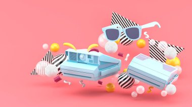 Pembe arkaplanda renkli toplarla çevrili polaroid kamera ve mavi gözlükler..