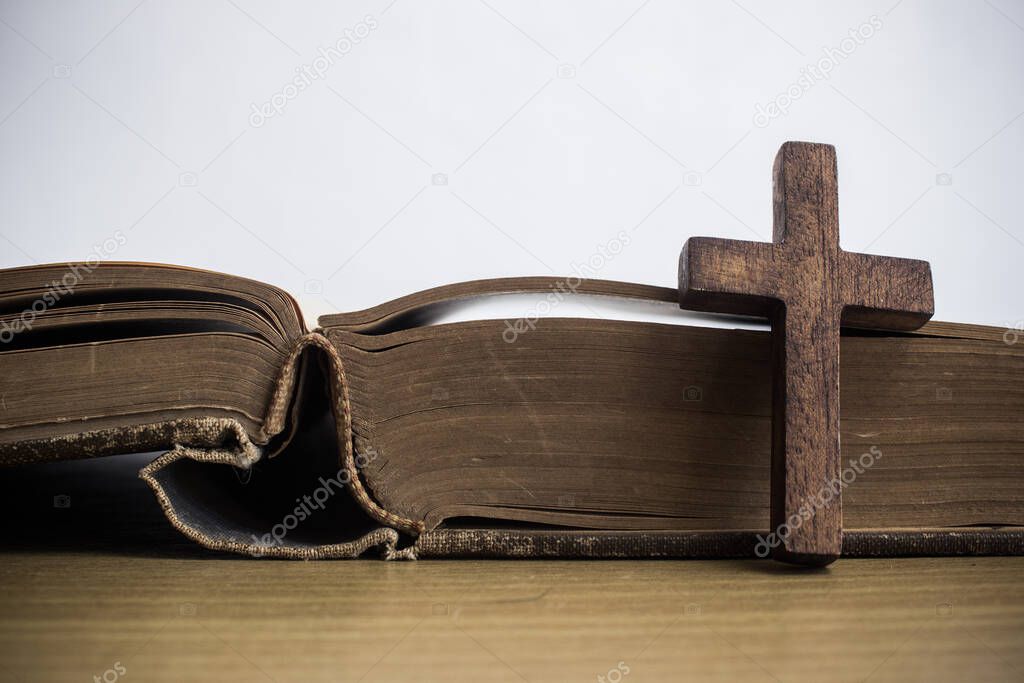 A sacred wooden cross with the Bible on the table