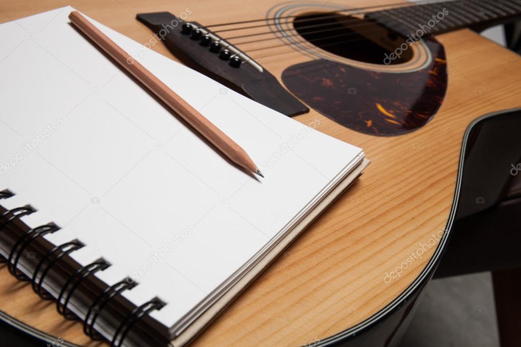 Notebook and pencil on guitar