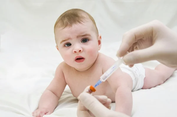 Baby is starring on syringe with immunization vaccine — Stock Photo, Image