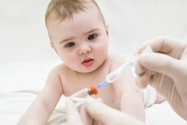 Baby girl  is starring on syringe with  vaccine — Stock Photo, Image