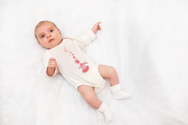 Retrato de una niña pequeña en su cama blanca . —  Fotos de Stock