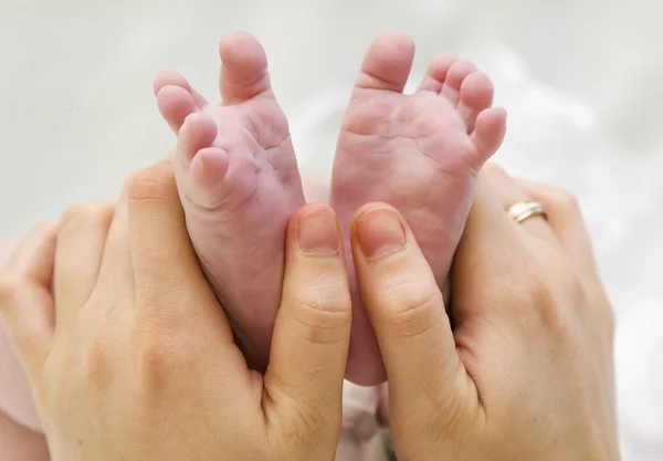 Нога младенца в руках матери крупным планом — стоковое фото