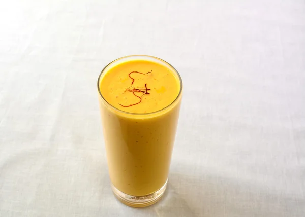 Манго Ласси в стакане, сладкий индийский смузи, посыпанный шафраном Лицензионные Стоковые Фото