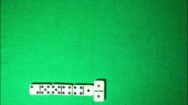 Yeşil kumaş arka plan üzerinde stop motion domino oyunu. Sarmal formu.