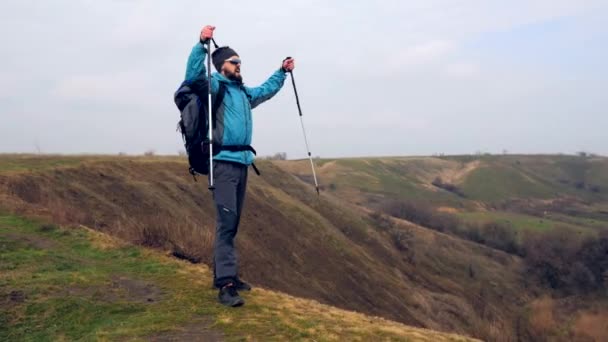 Hombre turista en una chaqueta azul con una mochila disfruta de su escalada — Vídeo de stock