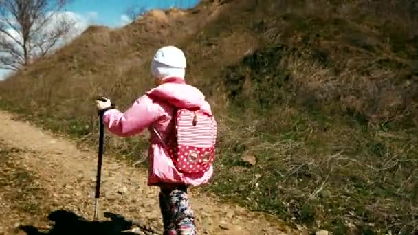 小女孩名徒步旅行者在一个背包和登山杆与粉红色的外套走在峡谷中 — 图库视频影像