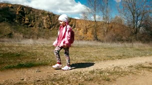 Petite fille randonneuse dans une veste rose avec un sac à dos marche dans le canyon — Video