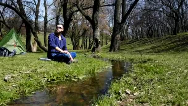 Jovem caminhante relaxa perto do riacho — Vídeo de Stock
