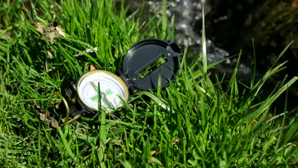 Brújula en la hierba cerca del arroyo litro — Vídeo de stock