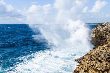 Güçlü dalgalar kayalık bir sahilde eziliyor.