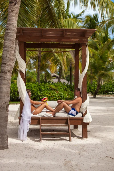 Man och hustru koppla av på solstolar på stranden — Stockfoto