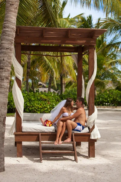 Man och hustru koppla av på solstolar på stranden — Stockfoto