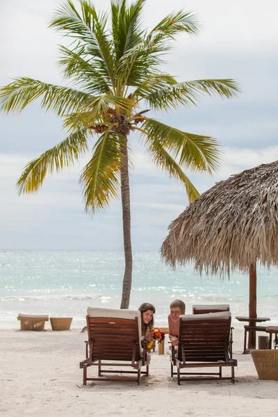 Husband and wife relaxing on sunbeds at the beach — Stock Photo, Image