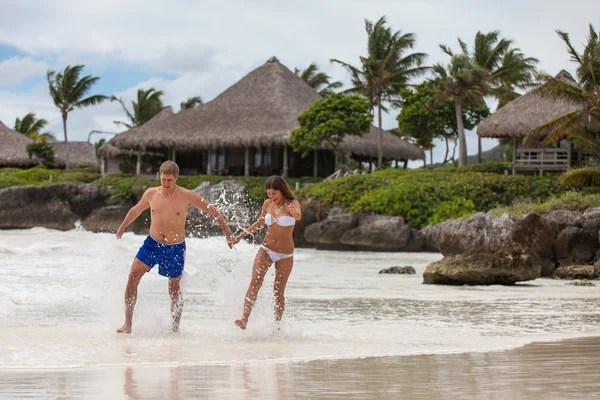 Couple courant à travers les vagues sur la plage vacances — Photo