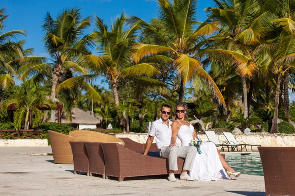 Young wedding couple sitting on the sunbed — Stock Photo, Image